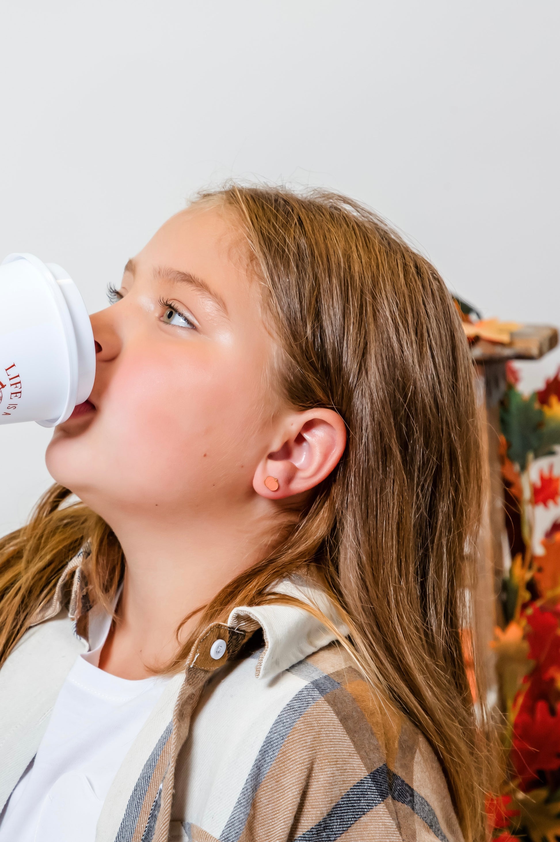 girl drinking from cup and wearing gold flatback pumpkin stud